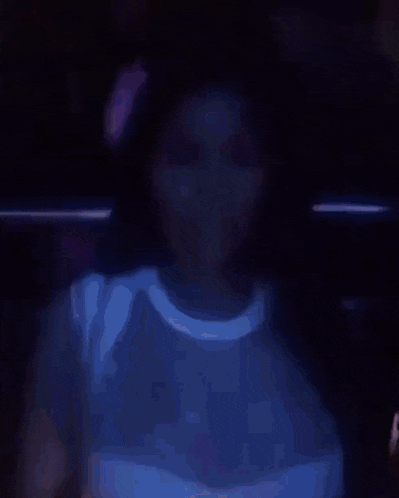 a woman in a white shirt is making a funny face in a dark room