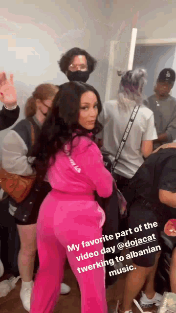 a woman in a pink outfit is standing in front of a crowd of people