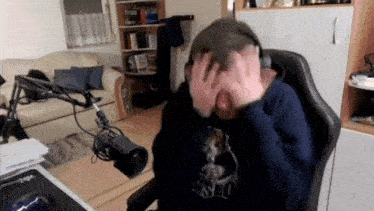 a man wearing headphones is sitting in a chair in front of a microphone in a living room .