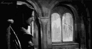 a black and white photo of a man standing next to a window .