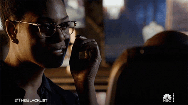 a woman wearing glasses is talking on a cell phone with #theblacklist on the bottom