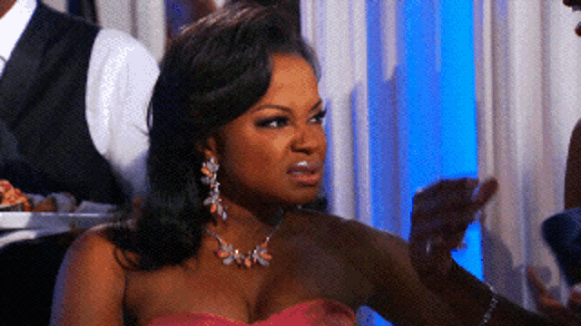 a woman in a pink dress and earrings looks angry