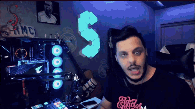 a man wearing an adidas shirt stands in front of a computer