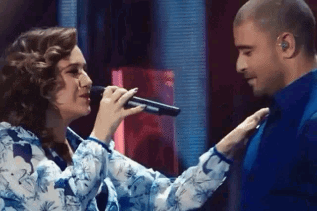 a woman is singing into a microphone next to a man