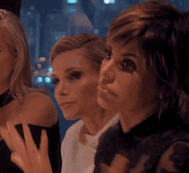 three women are standing next to each other and one of them is wearing a ring