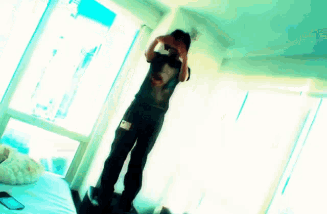 a man is standing in front of a large window with his hands behind his head