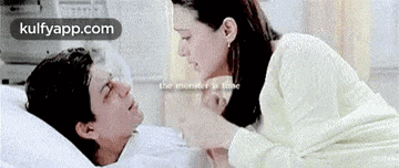 a man is laying in a hospital bed with a woman standing next to him .