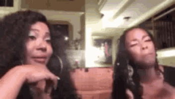 two women with long hair are sitting next to each other in a room .
