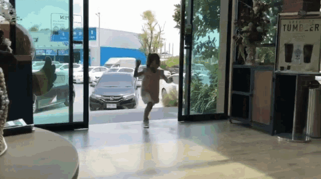 a little girl is running in front of a sign that says tumble