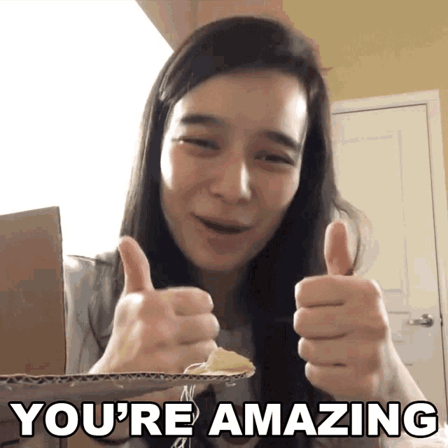 a woman giving a thumbs up with the words " you 're amazing " behind her