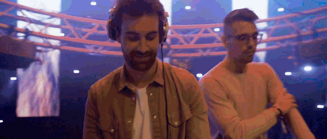 two men wearing headphones are playing music in a dark room .