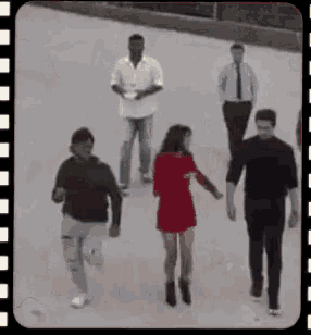 a group of people are walking down a street while holding hands .