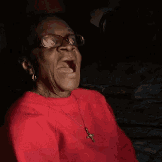 a woman in a red sweater with a cross necklace is yawning