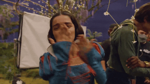a woman in a blue dress is covering her mouth with her hands