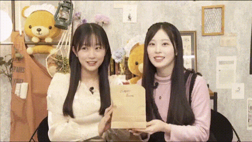 two girls are standing next to each other and one of them is holding a brown bag that says ' a ' on it
