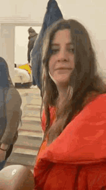 a woman wearing a red jacket and a mask is looking at the camera .