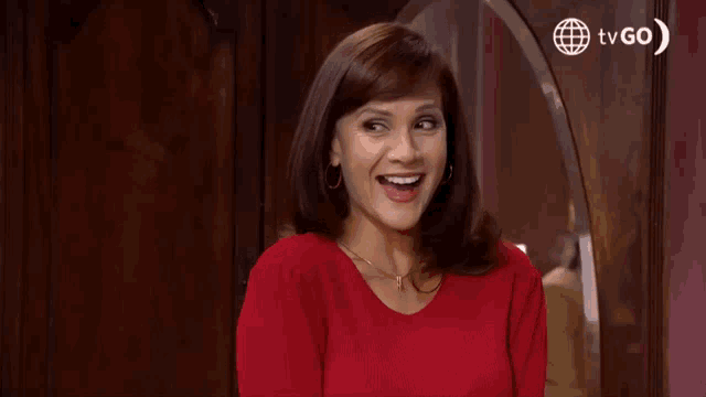 a woman in a red shirt is standing in front of a door .