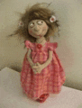 a doll in a pink dress with flowers in her hair is standing on a table .