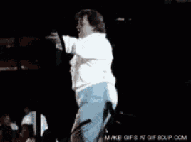 a man in a white shirt is dancing on a stage in front of a crowd