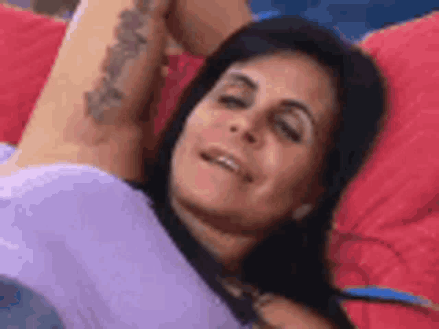 a woman with a tattoo on her arm is laying on a couch with her arms outstretched .
