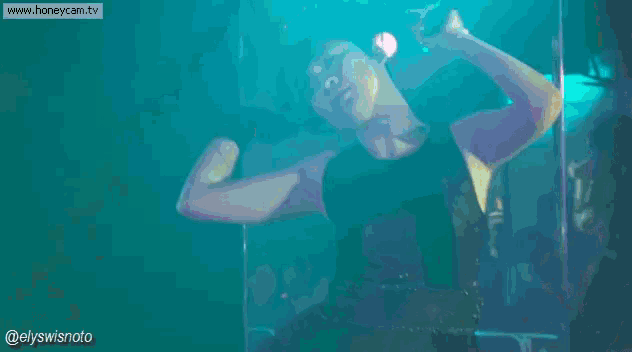 a woman in a black tank top is singing into a microphone .