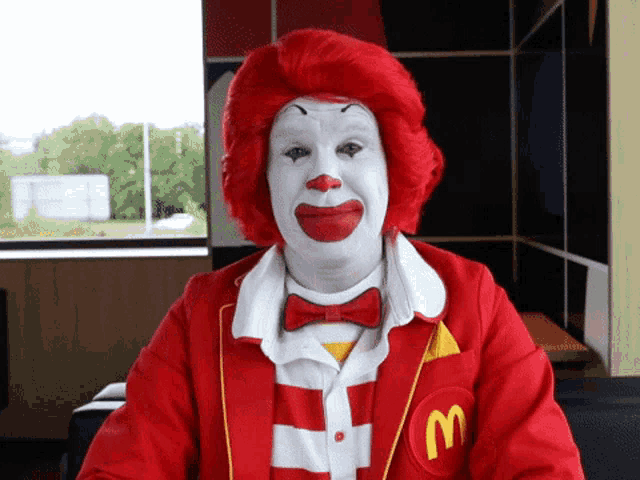 a man dressed as mcdonald 's clown with red hair and white face paint