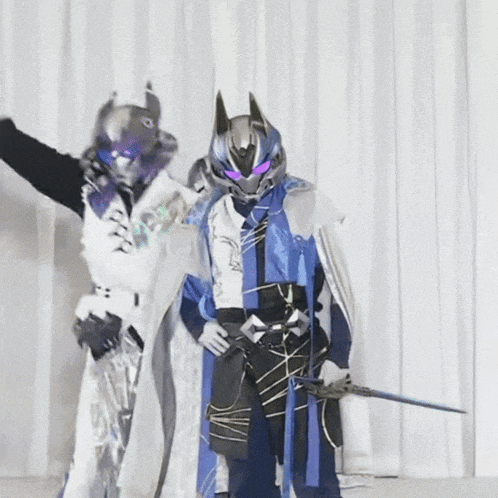 a man in a robot costume holds a sword while standing next to another man in a robot costume