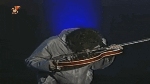 a man in a white jacket is playing a guitar on a stage