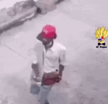 a man wearing a red hat is walking down a street holding a hammer .