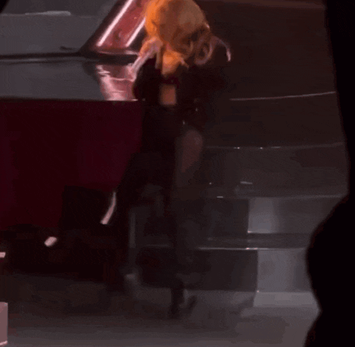a woman with blonde hair is standing on a stage with a microphone in her hand