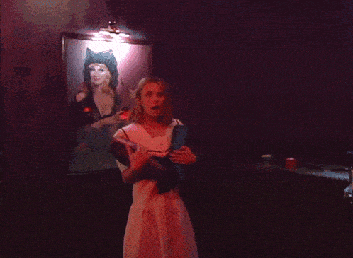 a woman is playing a video game in a dark room with a red light behind her