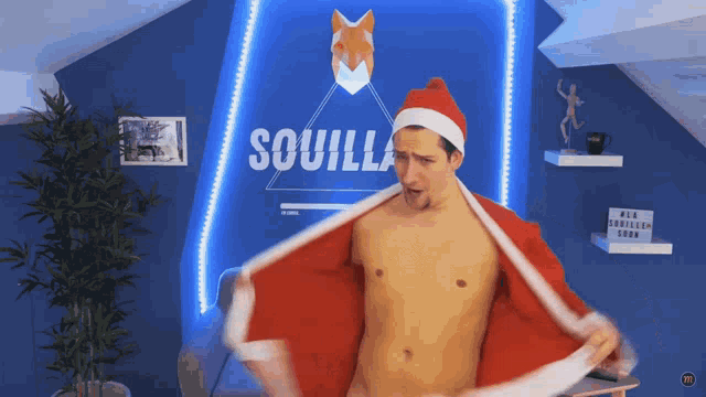 a shirtless man in a santa suit is standing in front of a sign that says soquilla