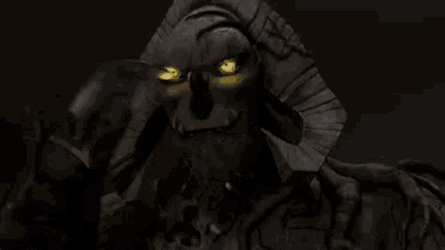 a statue of a skeleton with glowing eyes is holding a sword in his mouth .