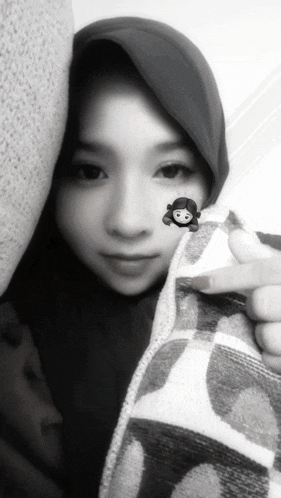 a black and white photo of a woman wearing a hijab and holding a blanket