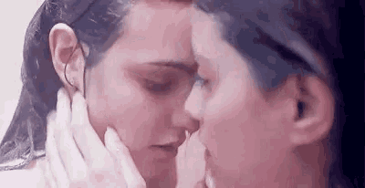 a couple of women are kissing each other in a shower .