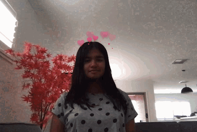 a girl wearing a polka dot shirt with hearts on her head
