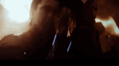 a close up of a person 's face in a dark room with a light behind them .