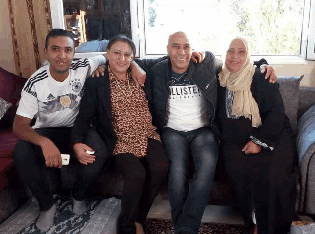 a man wearing a hollister t-shirt sits on a couch with other people