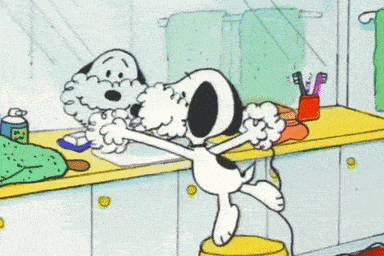 a cartoon of snoopy standing on a stool in a bathroom with a towel on his head