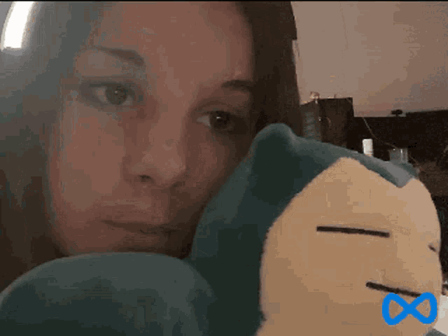 a woman holding a stuffed animal with a blue infinity symbol on the bottom