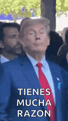 a man in a suit and tie is standing in front of a crowd and says tienes mucha razon .
