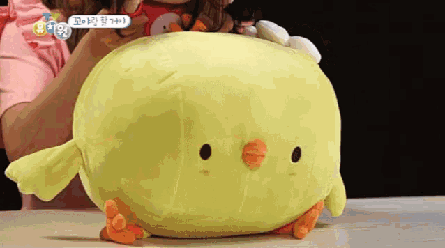 a stuffed yellow chicken is being held by a woman