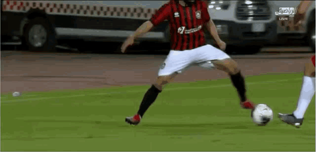a soccer player in a red and black jersey kicks a soccer ball