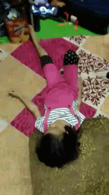 a little girl laying on her back on a rug