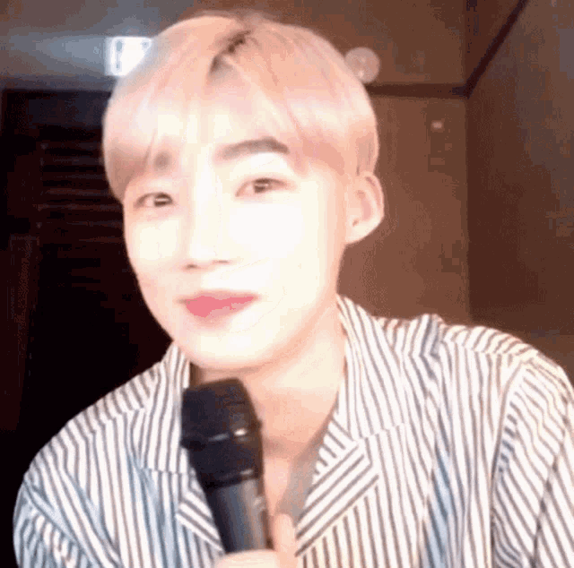 a young man in a striped shirt is holding a microphone