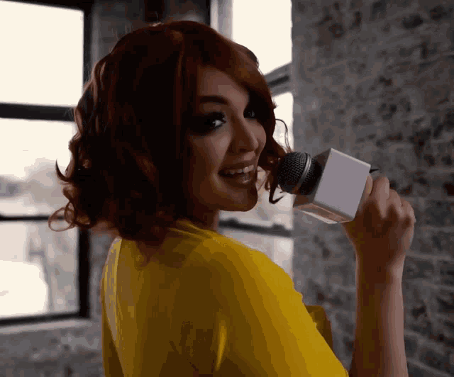 a woman with red hair is holding a microphone in her mouth