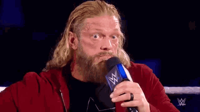 a man with a beard is holding a microphone in his hand and making a funny face .