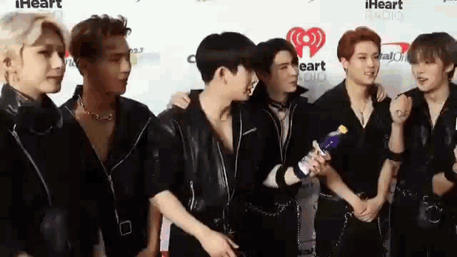 a group of young men are standing next to each other on a red carpet at an event .