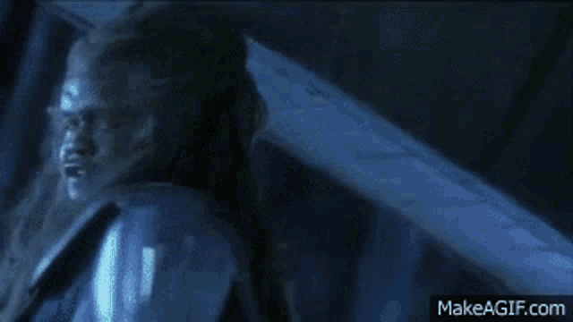 a person is holding a knife in their hand in front of a river in a dark room .