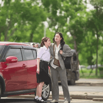 two women standing next to each other in front of a red suv